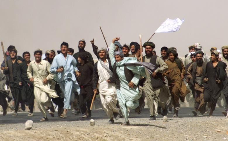 A mob of pro-Taliban Afghan refugees run to attack members of the international press traveling in a convoy near Quetta, Pakistan, near the Afghan border, October 10, 2001. REUTERS/Jerry Lampen