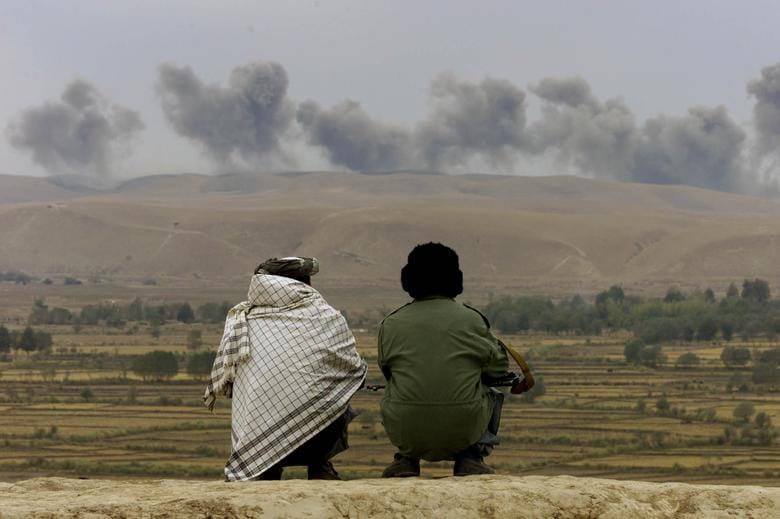 Two Northern Alliance soldiers watch as dust and smoke rises after explosions on Taliban positions near the village of Ai-Khanum in northern Afghanistan, November 1, 2001. REUTERS/Vasily Fedosenko