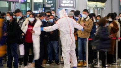 A security guard blocks an exit as he directs people to scan a QR code to track their health status at Shanghai Hongqiao Railway Station