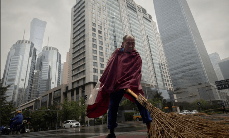 A worker sweeps a street in the Central Business District on a rainy day in Beijing, China, July 12, 2023. REUTERS:Thomas Peter